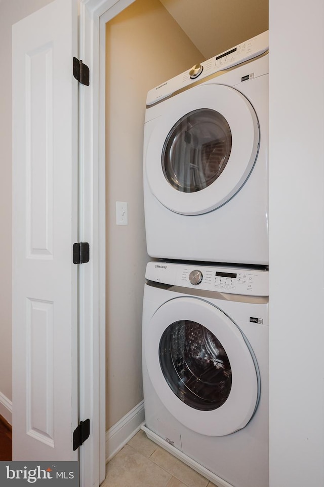 laundry area featuring stacked washer / drying machine and light tile patterned floors