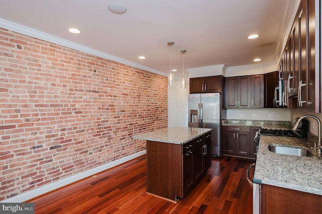 kitchen featuring sink, stainless steel appliances, light stone countertops, a kitchen island, and decorative light fixtures