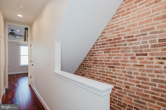 hall featuring brick wall and dark wood-type flooring