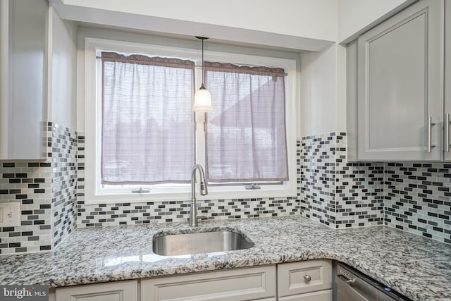 kitchen featuring stainless steel dishwasher, backsplash, sink, and pendant lighting