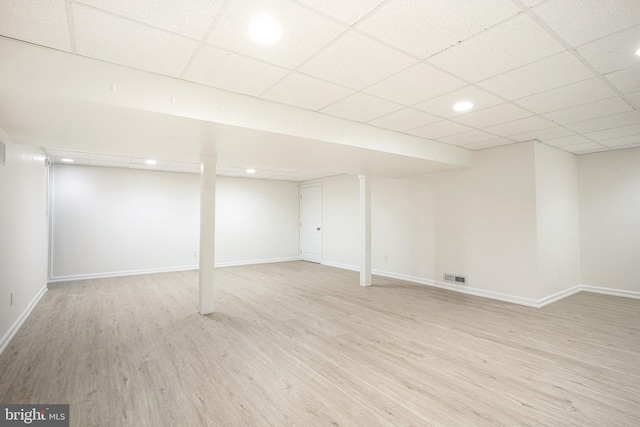 basement with light hardwood / wood-style floors and a paneled ceiling