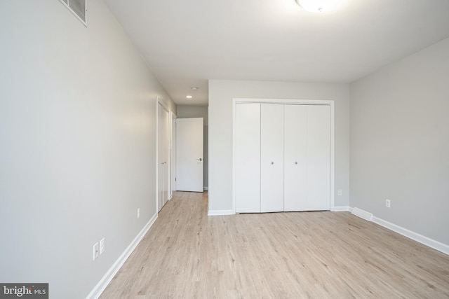 unfurnished bedroom with light wood-type flooring and a closet