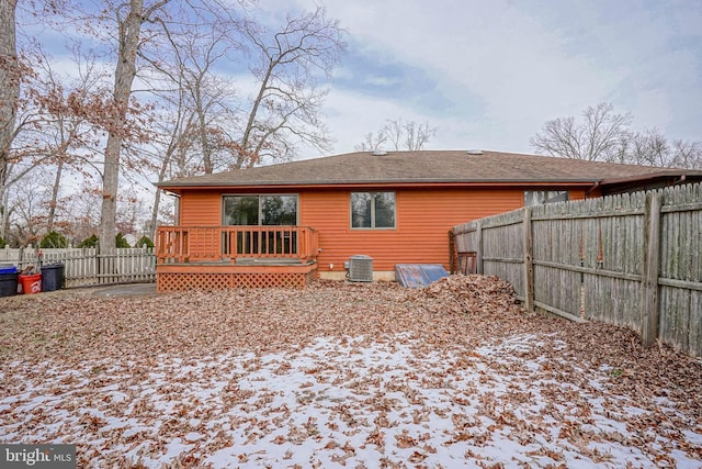 snow covered back of property featuring a deck and central AC