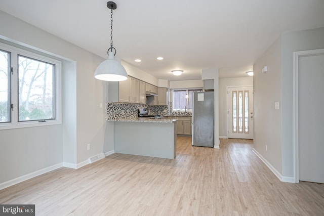 kitchen with backsplash, pendant lighting, kitchen peninsula, appliances with stainless steel finishes, and gray cabinetry