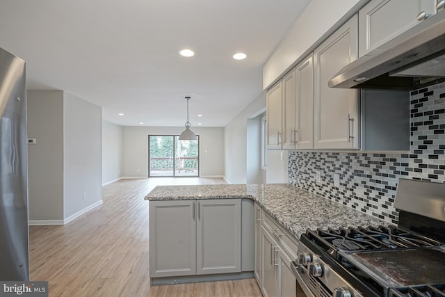 kitchen with wall chimney exhaust hood, backsplash, stainless steel range with gas cooktop, and light stone countertops