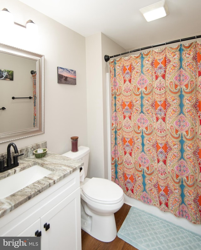 bathroom with vanity, hardwood / wood-style flooring, curtained shower, and toilet