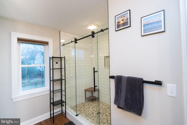 bathroom featuring hardwood / wood-style flooring, a shower with shower door, and a healthy amount of sunlight