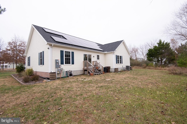 rear view of property featuring a yard, central air condition unit, and solar panels