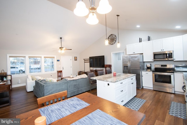 kitchen with pendant lighting, light stone counters, a kitchen island, and appliances with stainless steel finishes