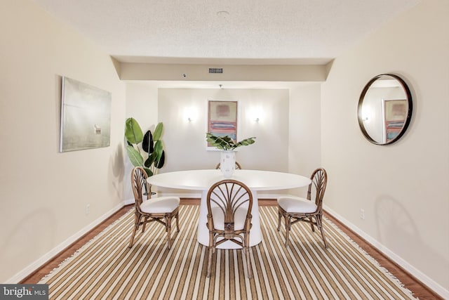 dining space with wood-type flooring and a textured ceiling