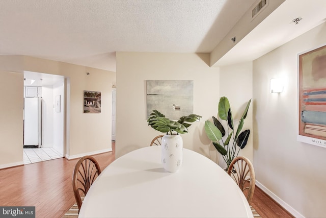 dining area with hardwood / wood-style flooring and a textured ceiling