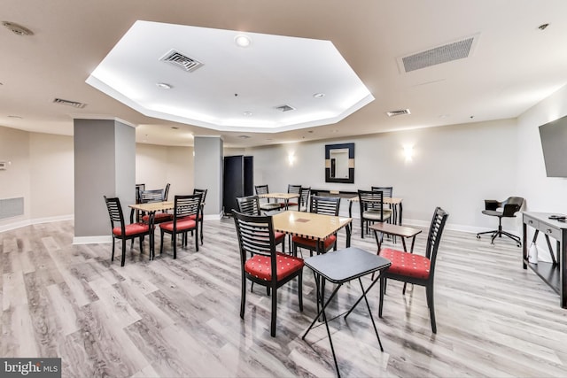 dining room with light hardwood / wood-style flooring and a tray ceiling