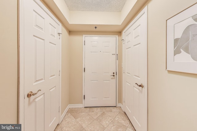 doorway to outside with a textured ceiling and light tile patterned flooring