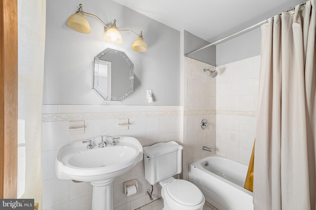 bathroom with toilet, a wainscoted wall, tile walls, and shower / tub combo with curtain