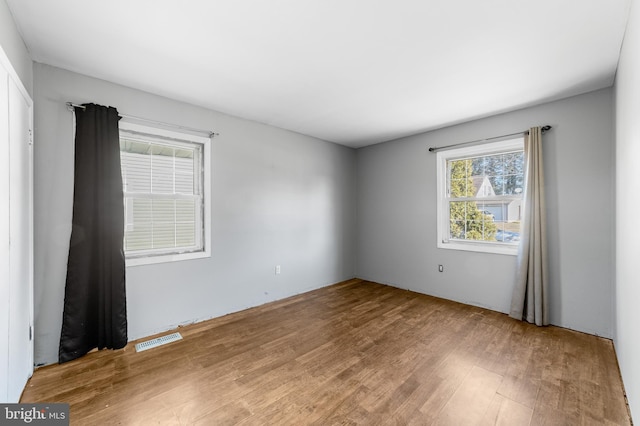 empty room with wood finished floors and visible vents