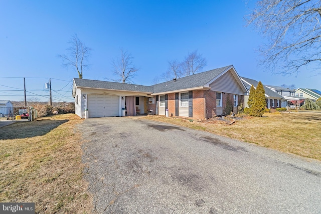 ranch-style house featuring a front yard, brick siding, driveway, and an attached garage