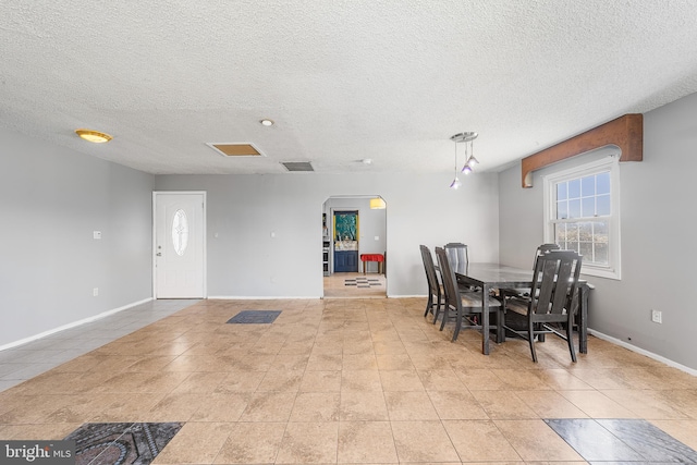 dining area featuring arched walkways, tile patterned flooring, visible vents, and baseboards