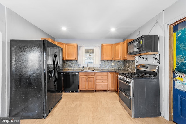 kitchen with dark countertops, a sink, backsplash, and black appliances