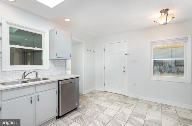 kitchen featuring visible vents, light countertops, decorative backsplash, stainless steel dishwasher, and a sink