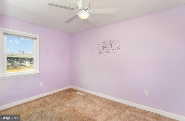 carpeted spare room with ceiling fan, baseboards, visible vents, and a textured ceiling