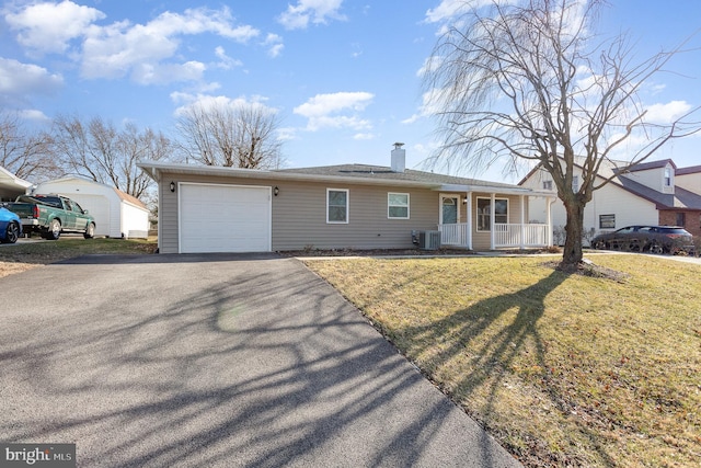 single story home featuring cooling unit, covered porch, a chimney, a front lawn, and a garage