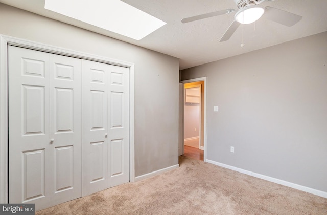 unfurnished bedroom with a skylight, baseboards, a closet, and carpet floors