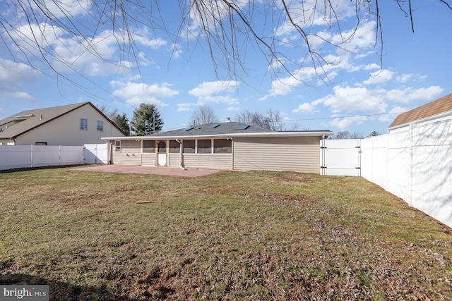 back of property featuring a gate, a fenced backyard, a sunroom, a patio area, and a lawn