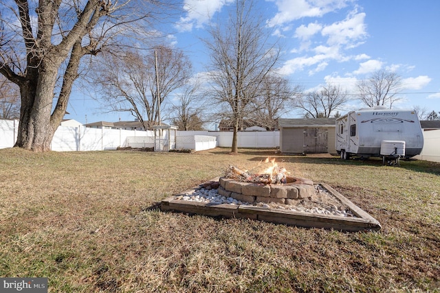 view of yard featuring an outdoor structure, fence private yard, a shed, and an outdoor fire pit