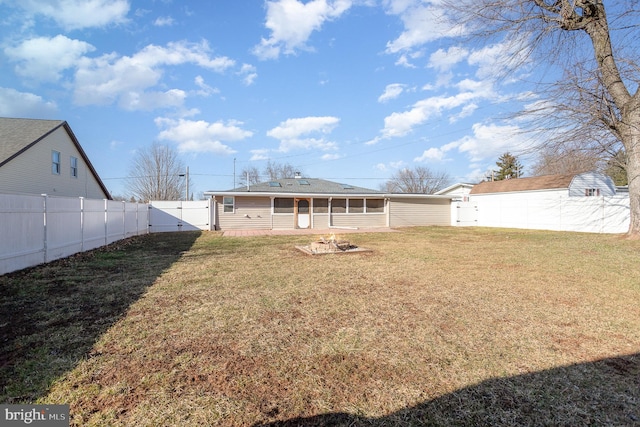 rear view of house featuring an outdoor fire pit, a fenced backyard, a sunroom, a yard, and a gate