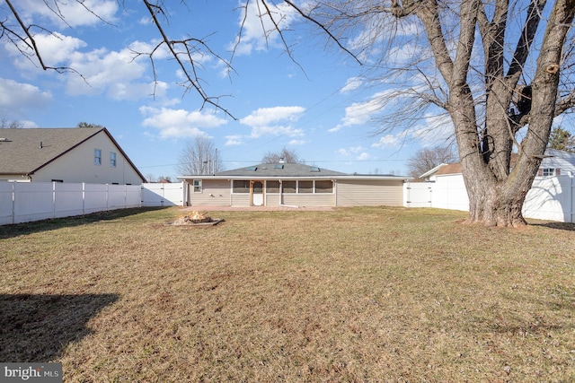 rear view of house with a yard, a fenced backyard, and a sunroom