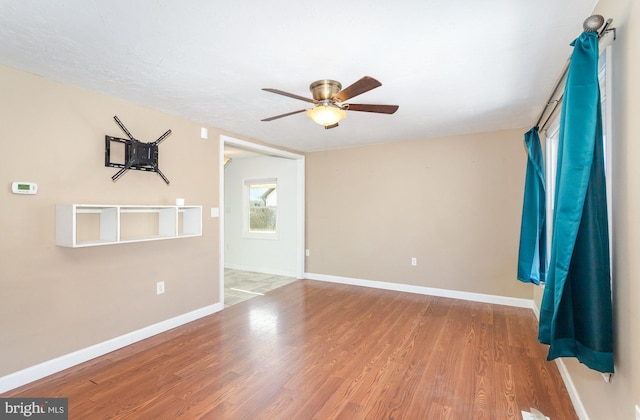 unfurnished room with wood finished floors, baseboards, and ceiling fan