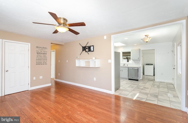 unfurnished living room with baseboards, a ceiling fan, and light wood finished floors