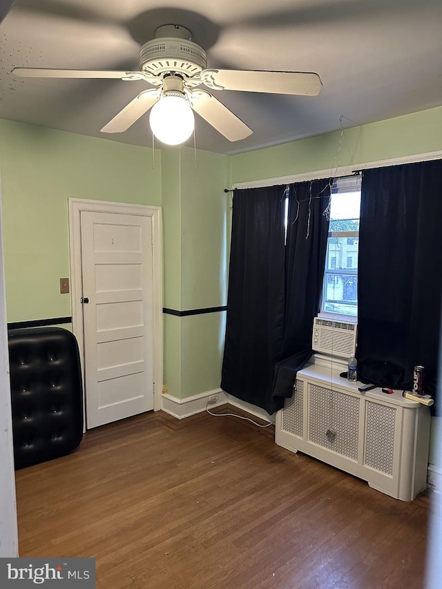 unfurnished bedroom with ceiling fan, radiator, cooling unit, and dark hardwood / wood-style floors