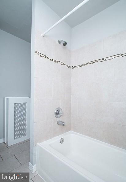 bathroom featuring tiled shower / bath combo and tile patterned flooring