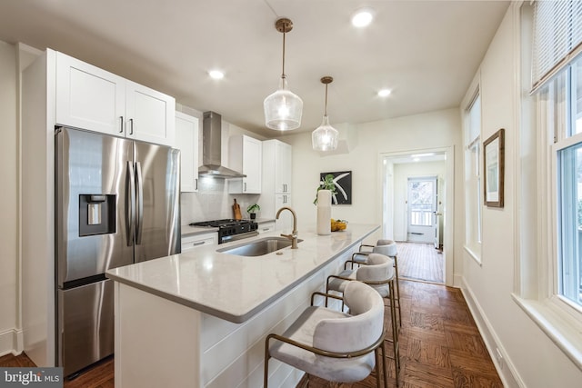 kitchen with pendant lighting, stainless steel refrigerator with ice dispenser, sink, dark parquet floors, and wall chimney exhaust hood