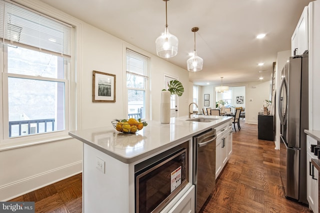 kitchen featuring decorative light fixtures, white cabinetry, a kitchen island with sink, and stainless steel appliances