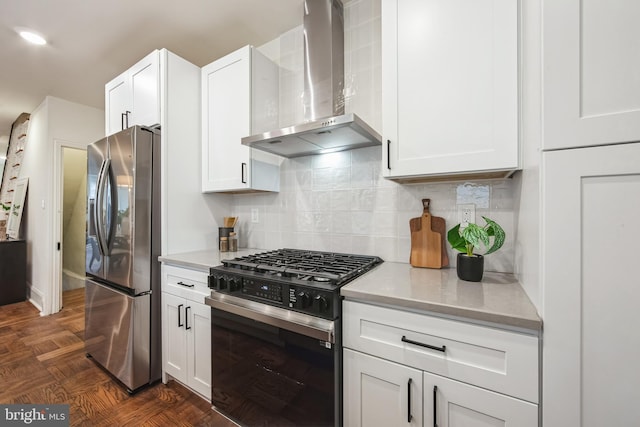 kitchen featuring range with gas cooktop, decorative backsplash, stainless steel fridge, white cabinets, and wall chimney exhaust hood