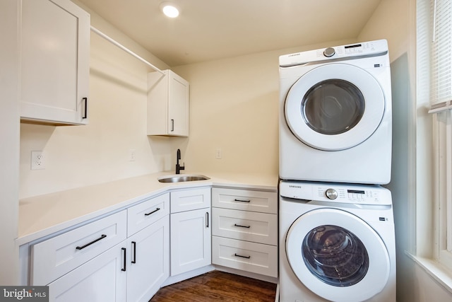 washroom featuring dark wood-type flooring, cabinets, stacked washer and clothes dryer, and sink