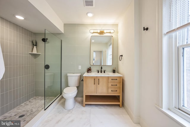 bathroom with tiled shower, vanity, and toilet