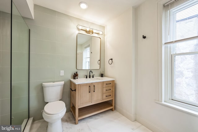 bathroom featuring toilet, a healthy amount of sunlight, tile walls, and vanity