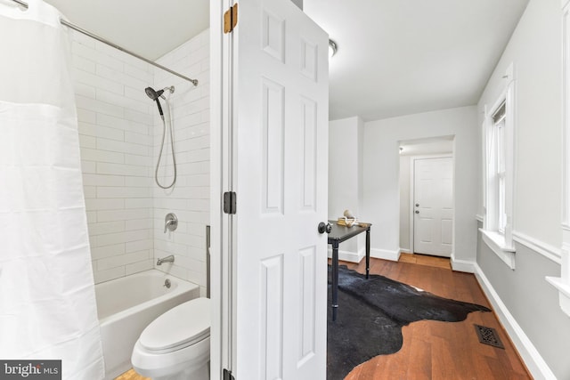 bathroom with toilet, wood-type flooring, and shower / bath combo