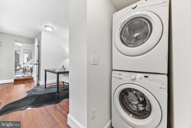 laundry area with stacked washing maching and dryer and hardwood / wood-style floors