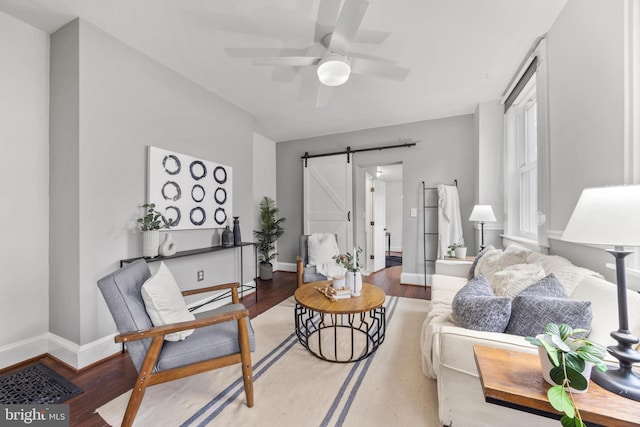 living room featuring ceiling fan, wood-type flooring, and a barn door