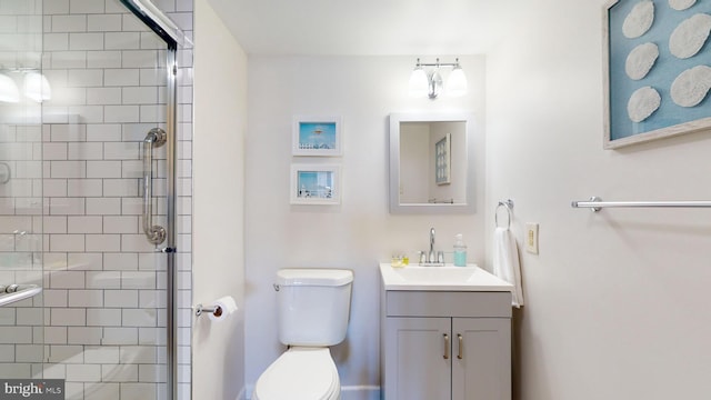 bathroom with toilet, vanity, and a shower with door