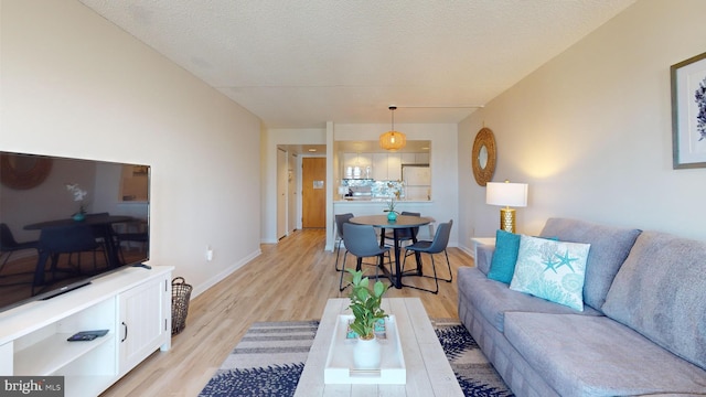 living room featuring light wood-type flooring and a textured ceiling