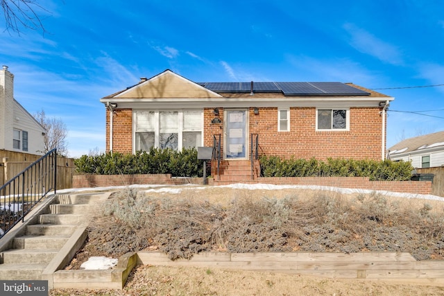 view of front of home with roof mounted solar panels and brick siding