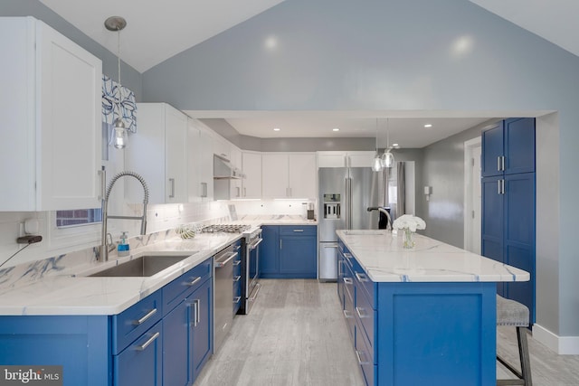 kitchen with under cabinet range hood, blue cabinets, stainless steel appliances, a sink, and light wood-style floors