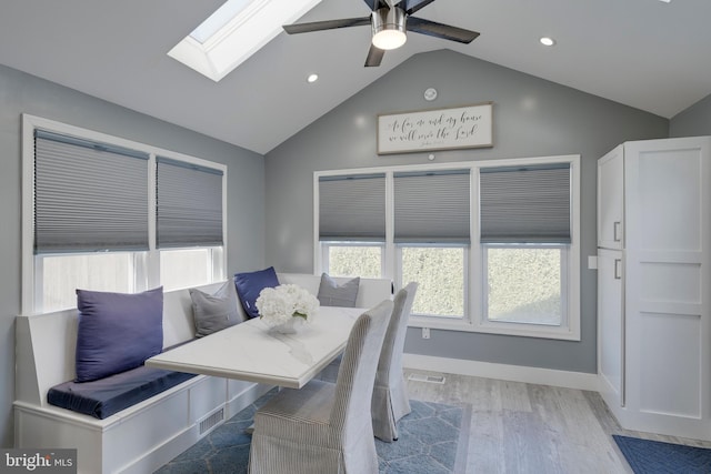 dining space featuring baseboards, vaulted ceiling with skylight, visible vents, and light wood-style floors