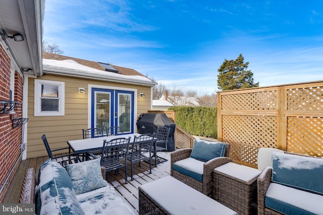 snow covered deck featuring grilling area, outdoor dining area, outdoor lounge area, and fence