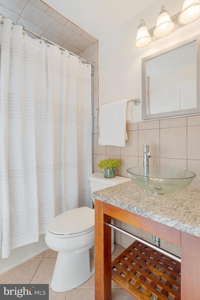 bathroom featuring toilet, a shower with curtain, tile patterned floors, vanity, and tile walls